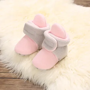 Close-up detail of soft pink and grey fleece baby shoes on a fluffy white rug background