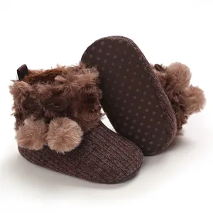 Detailed macro view of baby knitted booties featuring fluffy fur and pom-poms decoration.