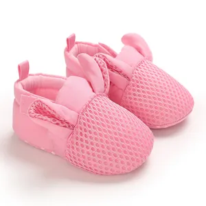 Dettaglio di scarpe da neonato in rete rosa con graziose orecchie da coniglio e suola morbida.
