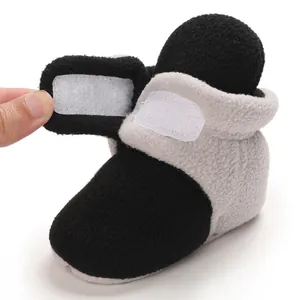 Detailed view of color-block baby fleece booties with adjustable velcro strap closure
