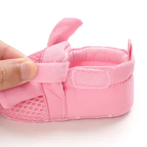 Dettaglio della scarpa primi passi per neonati in rete rosa con chiusura a strappo.