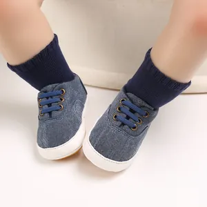 Gros plan de chaussures pour bébé en denim bleu avec semelles souples en caoutchouc blanc.