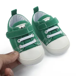 Gros plan de baskets bébé en toile verte avec embouts blancs et bandes velcro
