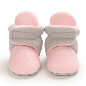 Close-up of pink and grey baby fleece booties with soft soles for autumn and winter.