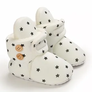 Detalle de botas de nieve blancas para bebé con estrellas negras y suave forro de felpa