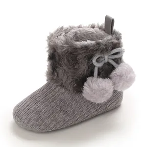 Grey baby knit cotton shoes with soft faux fur trim and cute pom-poms for baby girls.