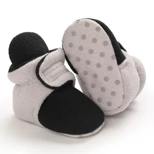 Detail macro view of black and grey fleece baby booties featuring an anti-slip soft sole