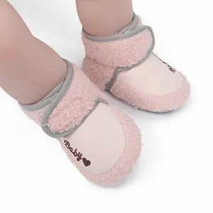 Close-up of pink baby winter boots featuring fluffy texture and heart embroidery.