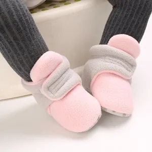 Detail of soft fleece baby booties in pink and grey with hook-and-loop closure