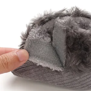 Close-up detail of a grey knit baby shoe with faux fur trim and Velcro closure mechanism