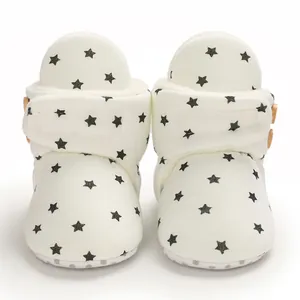 Primer plano de botas de invierno blancas para bebé con estrellas negras y forro de vellón