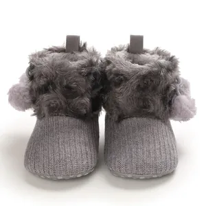 Detail view of cozy gray knitted baby boots with soft faux fur trim and pom-pom accents