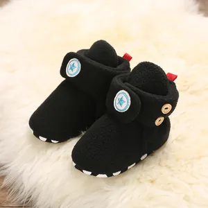 Primo piano di caldi scarponi da neve in pile nero per bambini su tappeto di peluche bianco
