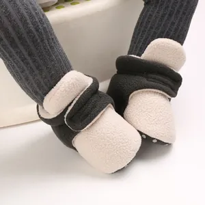 Detailed close-up of soft-soled baby fleece booties in a contrast cream and black colorway