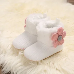 Close-up detail of white infant winter boots with pink flower and warm fleece lining