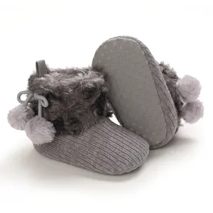 Close-up of cute grey baby knit booties featuring soft faux fur trim and decorative pom-poms