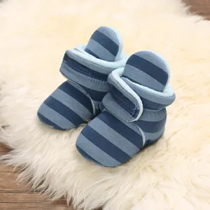 Nahaufnahme von blau gestreiften Babystiefeln mit warmem Plüschfutter auf Fellteppich.