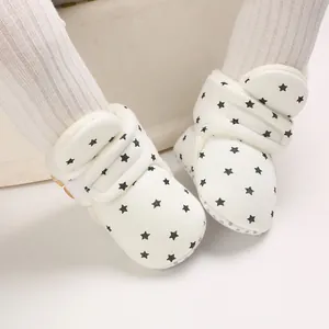 Primer plano de botas de nieve blancas para bebé con patrones de estrellas negras y forro polar