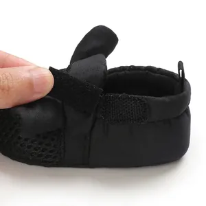 Dettaglio ravvicinato di scarpa per neonato in rete nera traspirante con chiusura a strappo