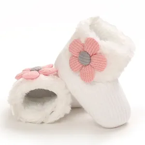 Detailed macro view of white winter baby booties with soft fleece lining and pink flower