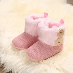 Κοντινό πλάνο από ροζ πλεκτές βρεφικές μπότες με ζεστή γούνα και ξύλινα κουμπιά