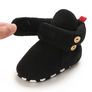 Dettaglio macro della scarpa neonato in pile nero con velcro e bottoni in legno