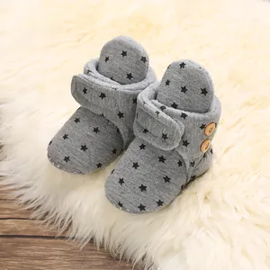 Detailed macro view of warm grey infant snow boots featuring black star patterns and wooden buttons