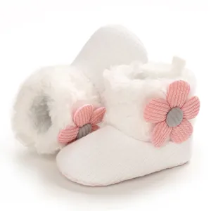 Close-up of soft white infant snow boots featuring cute pink flower and warm faux fur trim