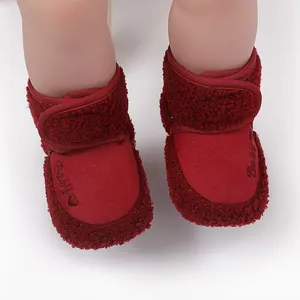Detailed view of red plush infant winter boots with secure velcro strap and heart detail