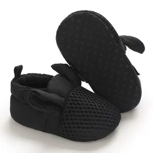 Dettaglio di mesh traspirante e suola morbida antiscivolo su scarpe nere per neonati