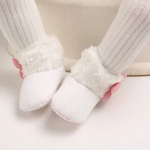 Detail shot of white infant winter snow boots featuring soft faux fur trim and pink bows