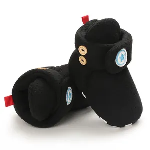 Detailopname van zwarte pluche babysneeuwlaarzen met houten knopen en blauw sterlogo.