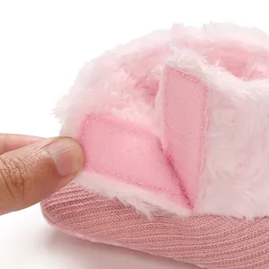 Close-up detail of pink baby bootie showing the adjustable velcro strap for easy wear.