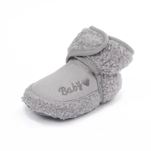 Detail of soft grey fluffy fleece baby bootie featuring a cute embroidered heart and text