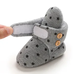 Detalle de botas de nieve grises para bebé con patrón de estrellas y forro de vellón cálido