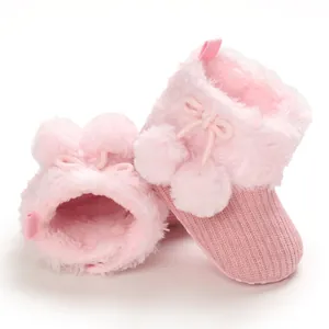 Detail of cute pink baby booties with soft plush fur and decorative pom-poms