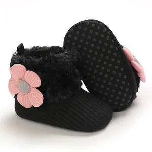Close-up of black baby snow boots with fuzzy lining and pink flower decoration detail.