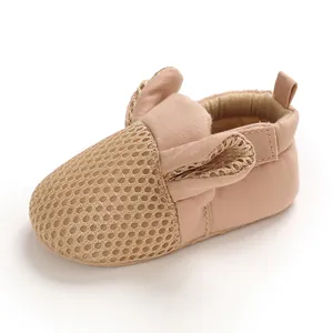 Dettaglio di scarpe per neonati in rete traspirante con graziose orecchie beige