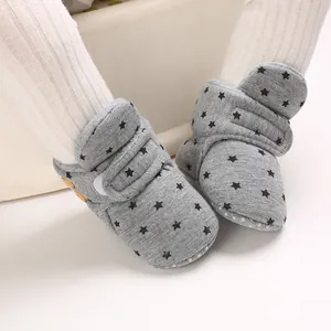 Detalle de botas de nieve grises para bebé con patrón de estrellas y suela blanda.