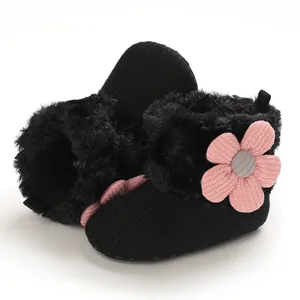 Detailed macro view of black baby winter boots featuring a decorative pink knit flower