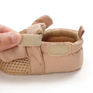 Dettaglio di scarpa da camminata per neonati in rete con cinturino a strappo regolabile.