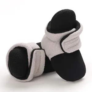 Detail view of soft fleece baby booties with color-block design and adjustable strap