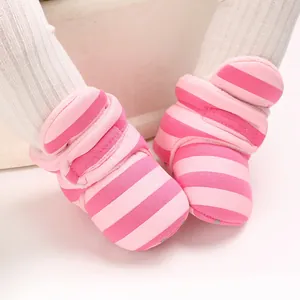 Nahaufnahme des weichen Stoffes und des rosa gestreiften Musters warmer Babystiefel