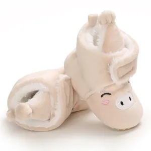 Gros plan de bottes de neige pour bébé avec motif de cochon et doublure en peluche.