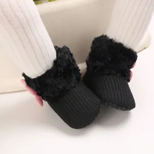 Detail of black baby snow boots with fur trim and pink bow for infants 0-1 year old