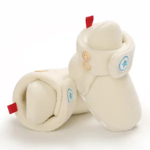 Dettaglio degli stivaletti da neve per neonati in pile crema con toppa a stella blu