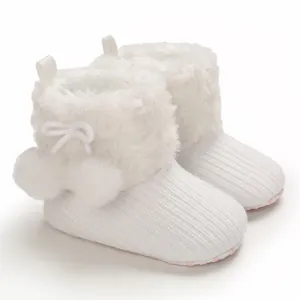 Detailed view of white baby princess boots with soft fur and decorative pom-poms