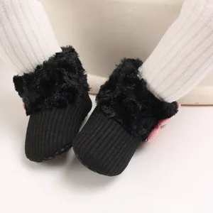 Close-up of black baby fleece snow boots with pink bow and soft anti-slip sole