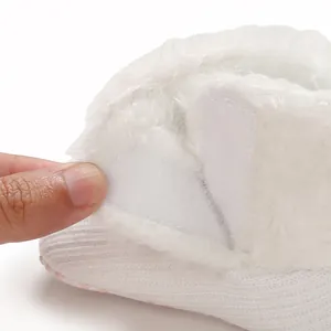 Close-up detail of white infant knit booties with soft fuzzy lining and adjustable velcro closure