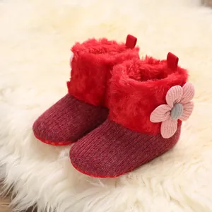 Warm red baby winter boots with soft fleece lining and cute flower detail on fur rug.